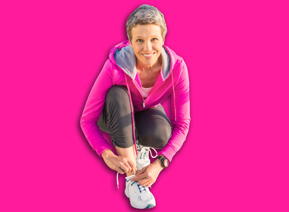 Portrait of smiling sporty woman tying her shoelace at promenade on a sunny day
