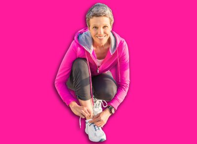 Portrait of smiling sporty woman tying her shoelace at promenade on a sunny day