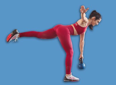 Side view of woman doing single leg kettlebell deadlift standing in modern gym and balancing