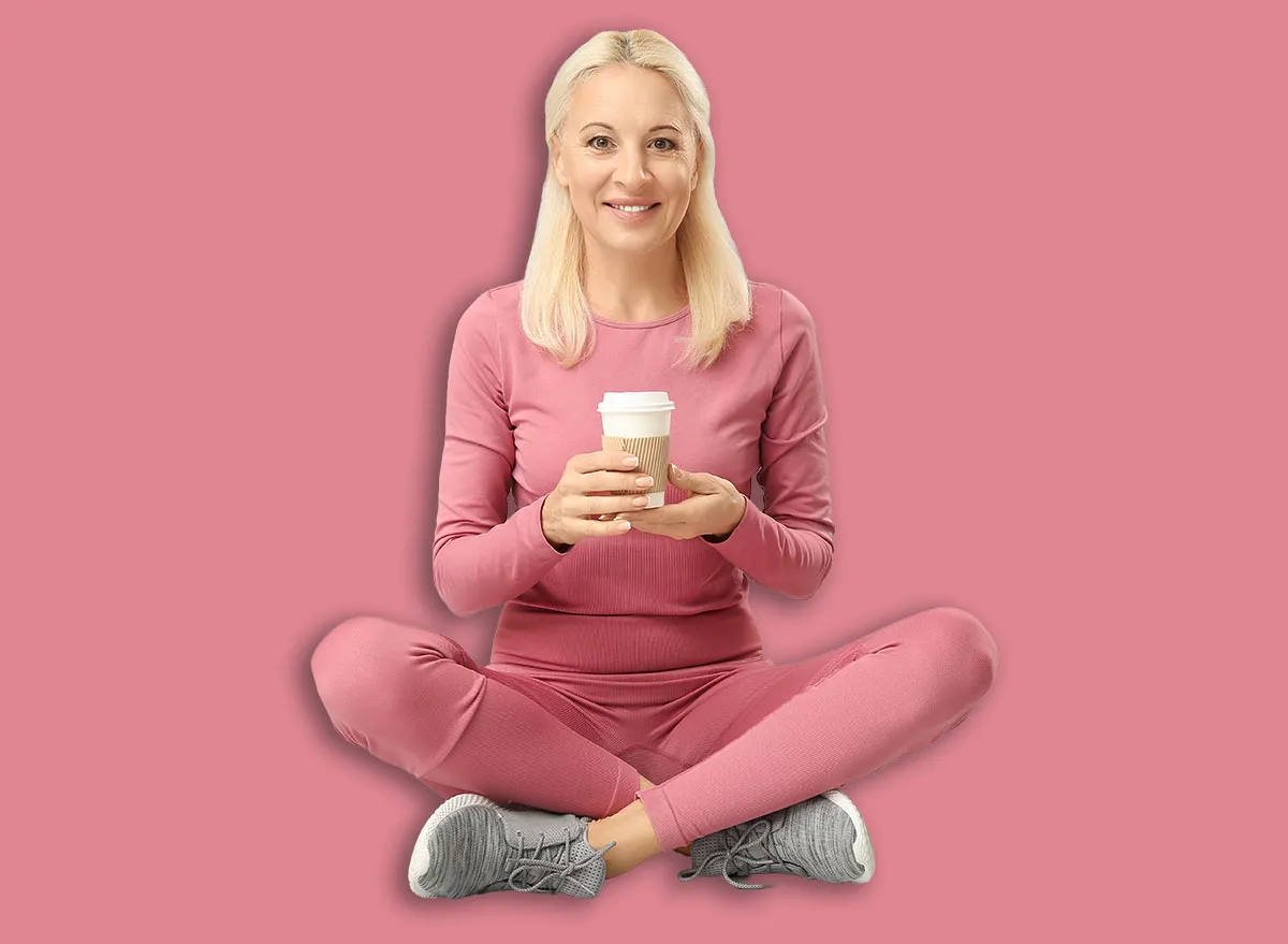 Mature woman in sportswear with cup of coffee sitting on grey background