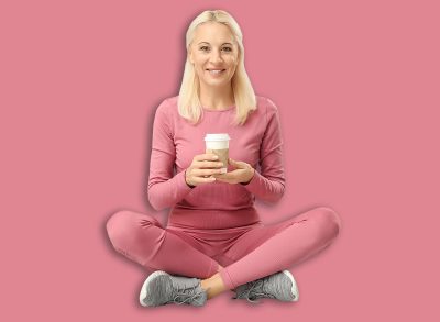 Mature woman in sportswear with cup of coffee sitting on grey background