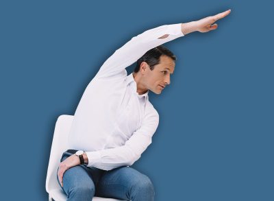 middle aged businessman doing side bend on chair at office