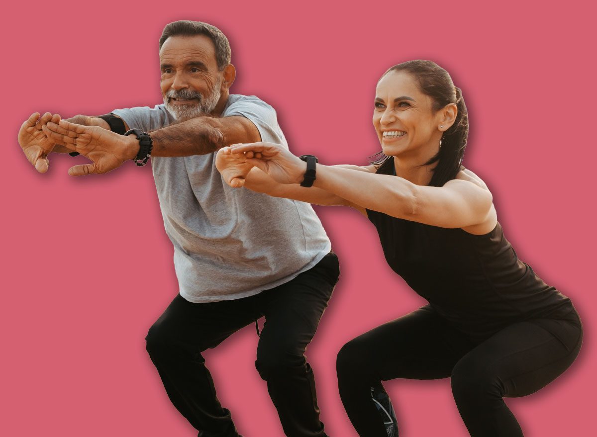 Happy senior caucasian couple in sportswear squats, enjoy training together on beach in morning, outdoor, full length. Health care, relationships, sports teamwork and active lifestyle