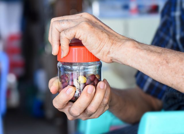 Asian Chinese man screwing the cap of glass bottle. Concept of hand muscle strength and power.