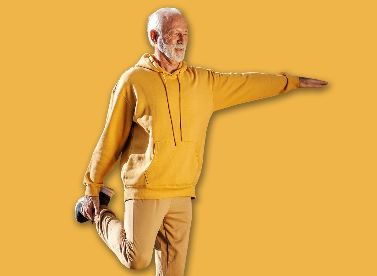 Full length of a fit old sportsman with healthy habits balancing on one foot and doing fitness exercises in nature.