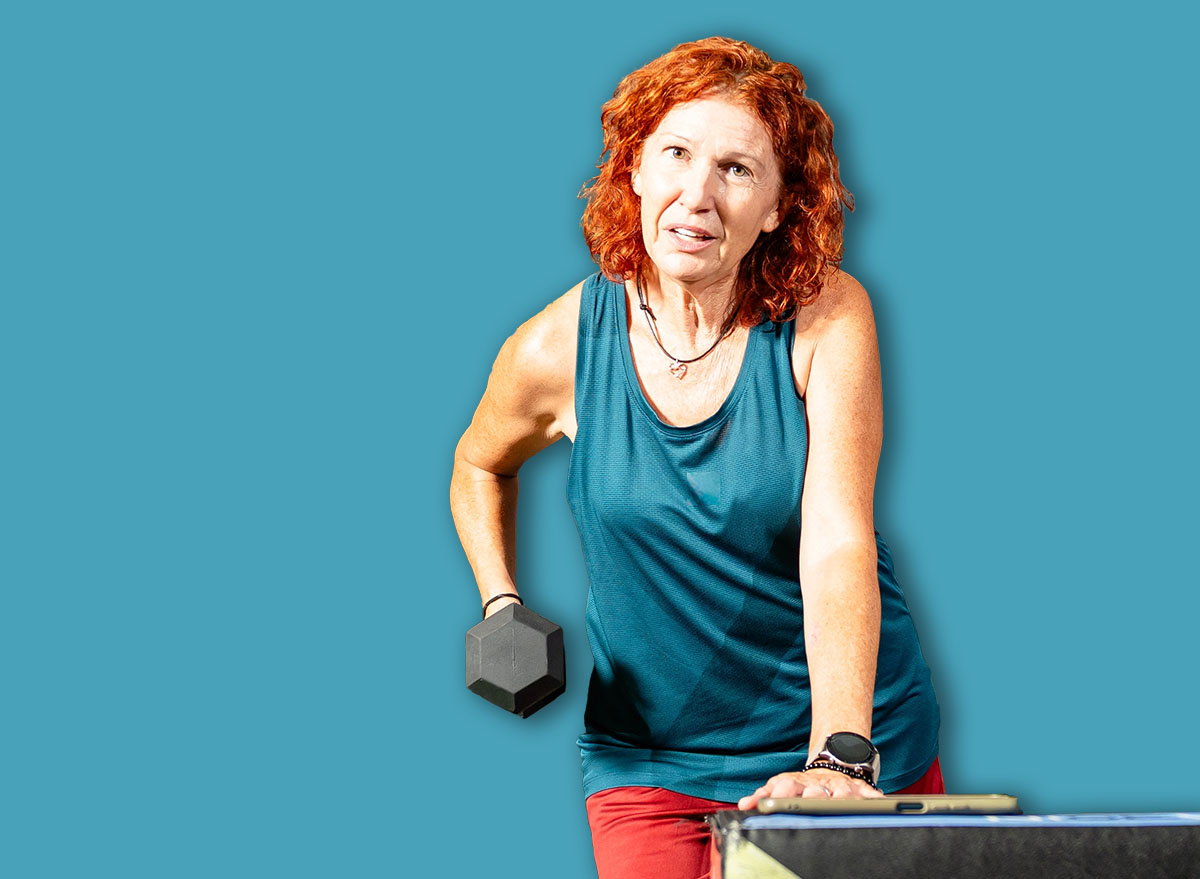 Senior woman performing single arm dumbbell row exercise in a modern gym
