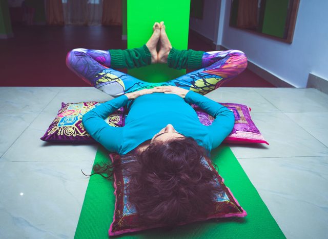 young woman in yoga relaxing pose with legs up the wall full body shot