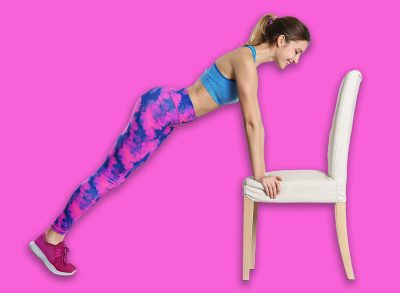 Young woman exercising with chair near white wall. Home fitness