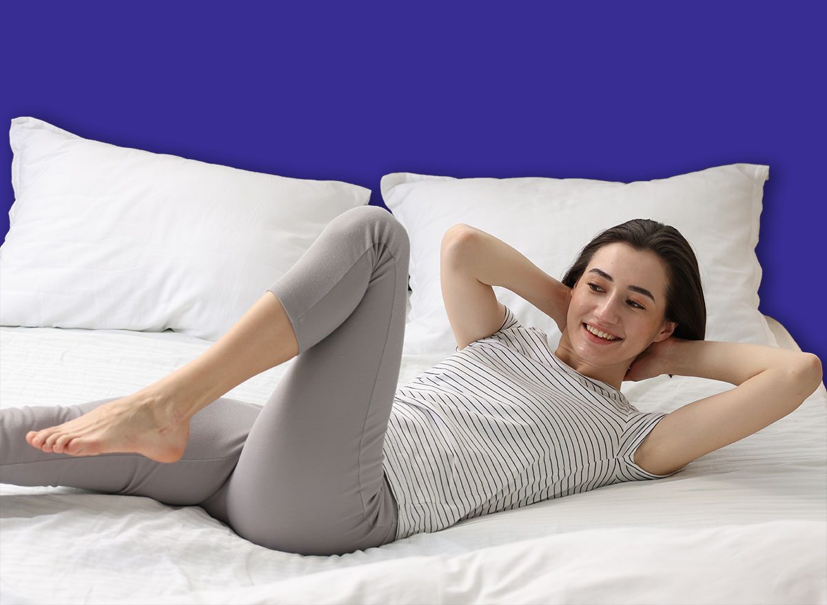 Young woman exercising on bed at home. Morning routine
