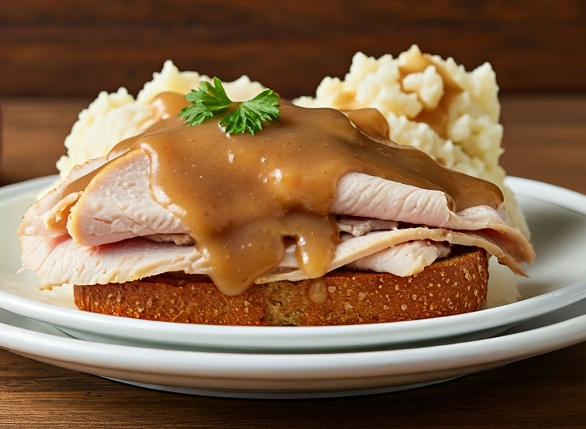 hot open-faced turkey sandwich with gravy and mashed potatoes on a white plate