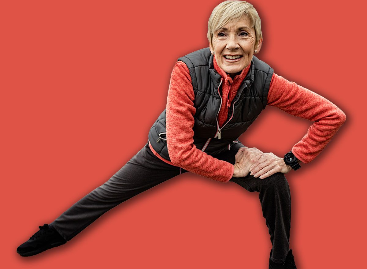 Active senior woman stretches her muscles before running through the city during the day.