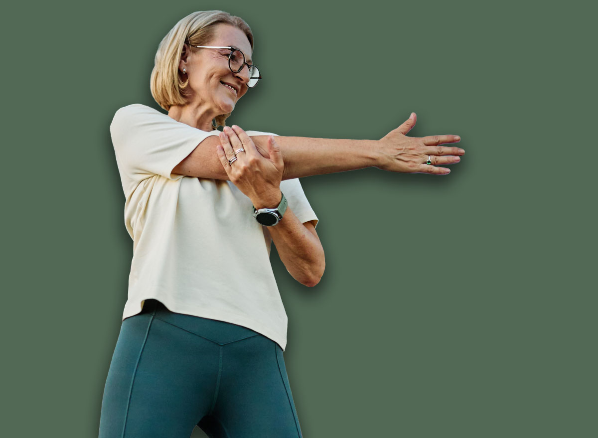Portrait of a middle aged mature beautiful sport woman smiling happy and confident. Standing and doing exercise and stretching in city park outdoors
