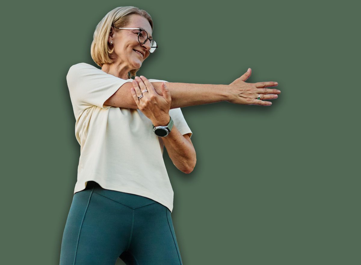 Portrait of a middle aged mature beautiful sport woman smiling happy and confident. Standing and doing exercise and stretching in city park outdoors