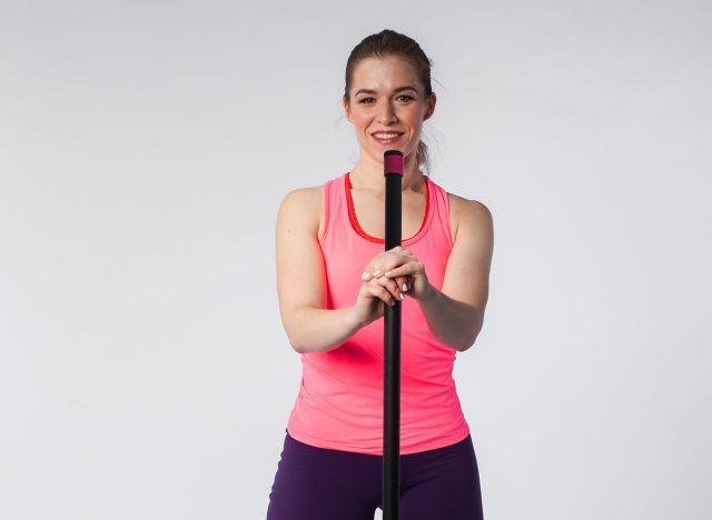 Young brunette woman posing with barbell on white