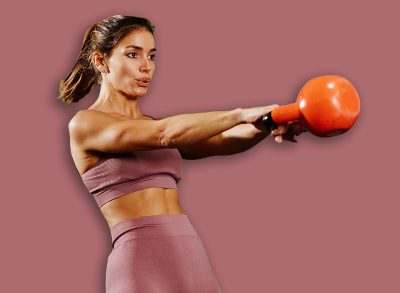Young woman performing kettlebell swing exercise during cross training at fitness club