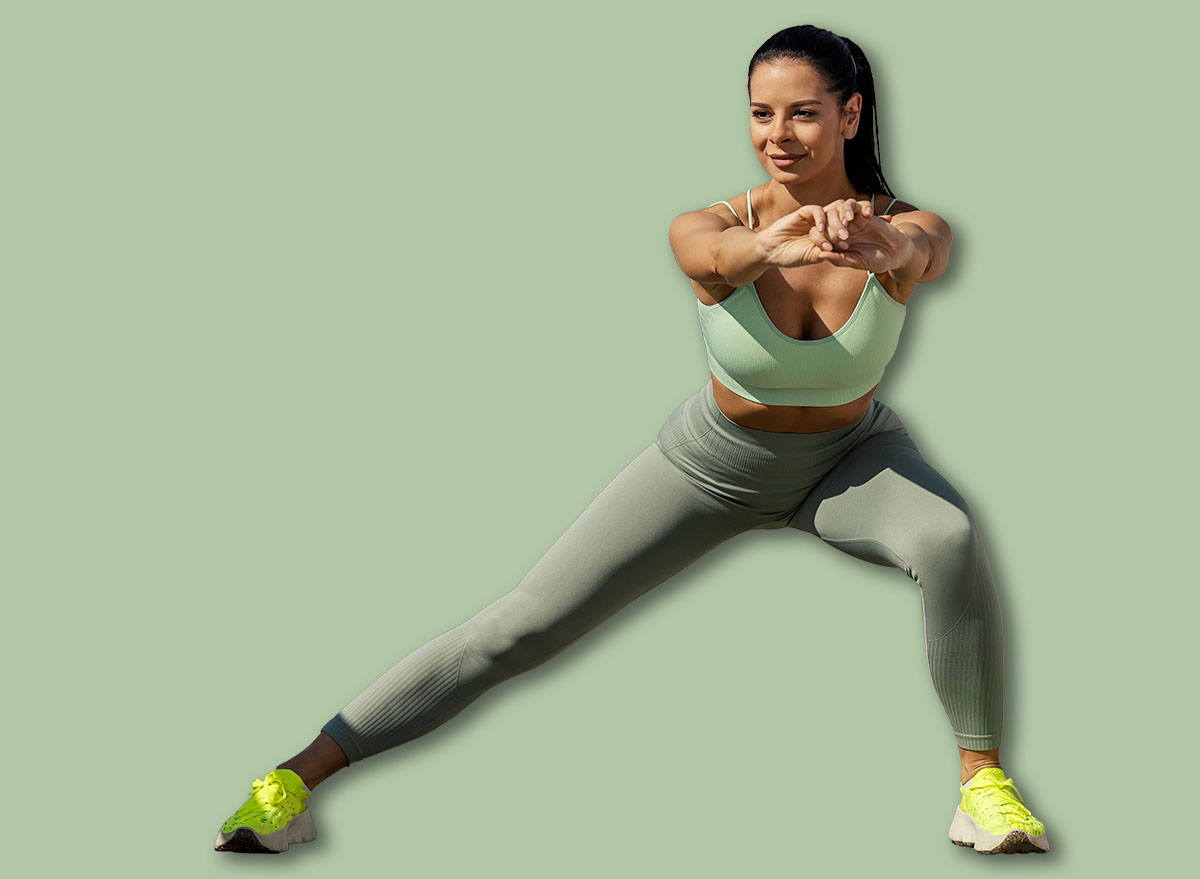 Full length of fit urban female athlete standing on a bridge downtown and doing side lunges.
