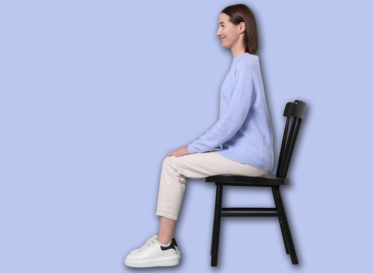 Woman with good posture sitting on chair against gray background