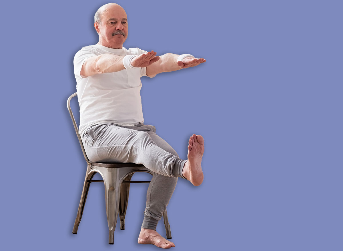 Elderly man practicing yoga asana or sport exercise for legs and hands on chair