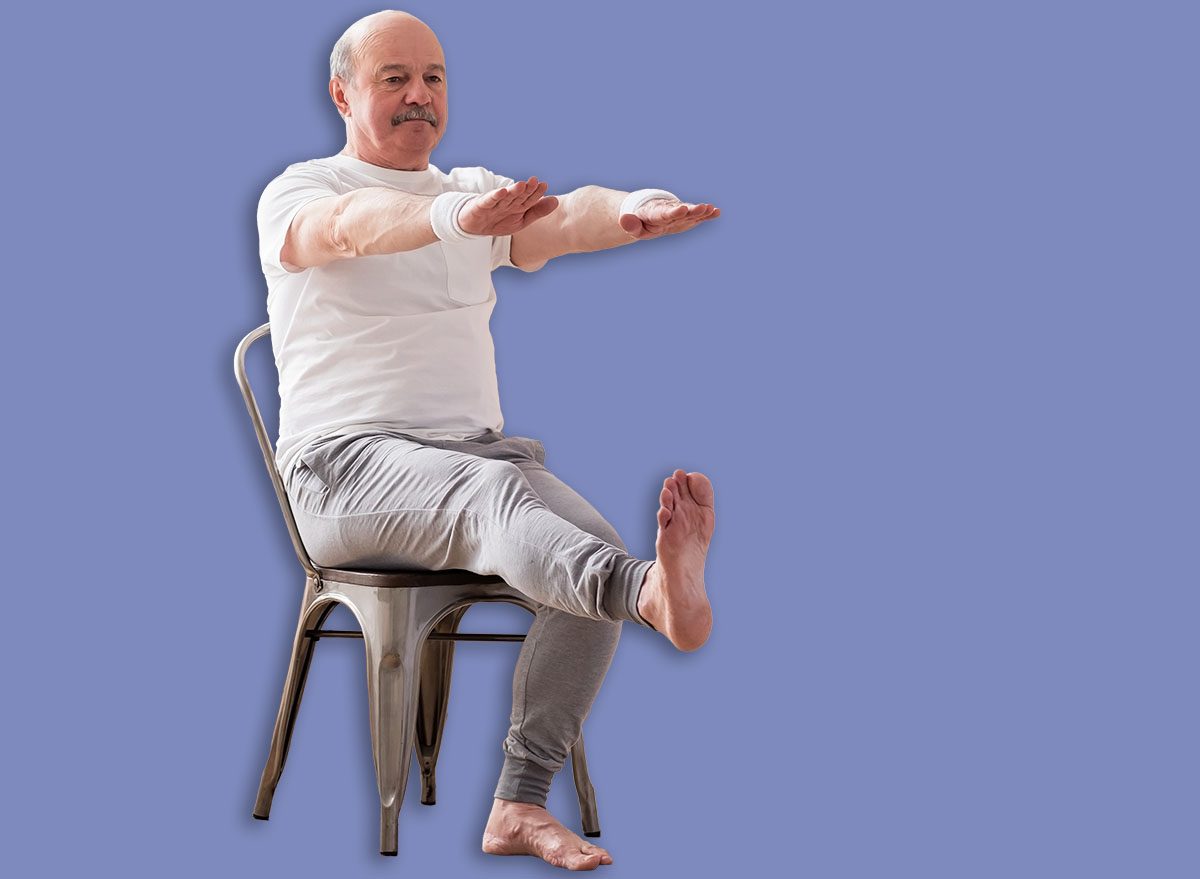 Elderly man practicing yoga asana or sport exercise for legs and hands on chair