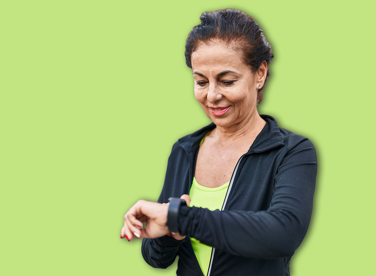 Middle age hispanic woman working out with smart watch outdoors