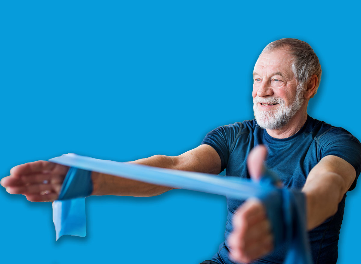 A senior couple indoors at home, doing exercise on the floor.
