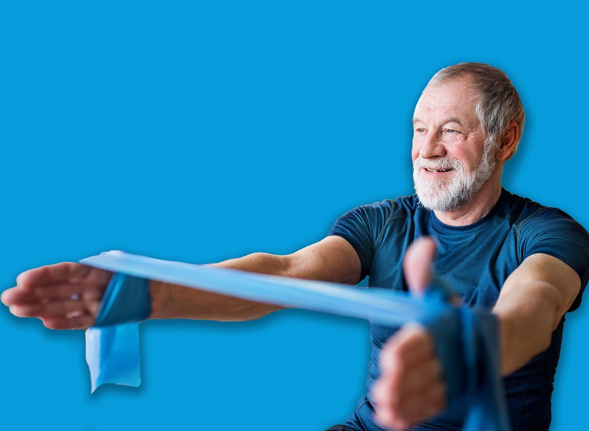 A senior couple indoors at home, doing exercise on the floor.
