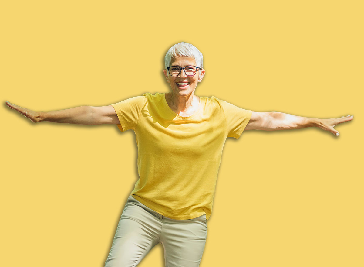 Balancing exercise outdoors. Mature woman standing on one leg, exercising balance