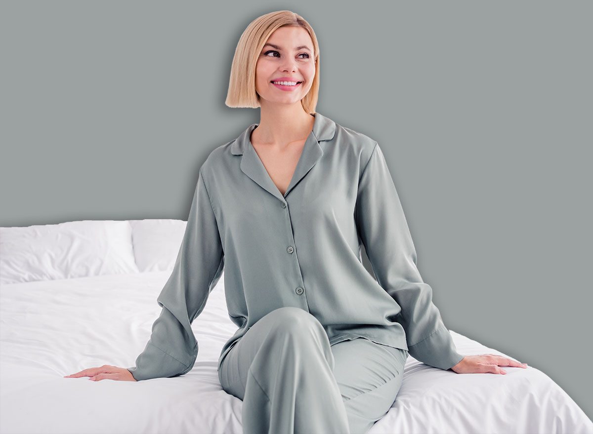 Photo of slumber happy girl wearing grey pajama looking curious in window sitting bedroom white cozy blanket and pillows isolated indoors