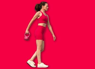 Sporty mid adult woman carrying a kettlebell weight, training outdoors. Red sports clothing.