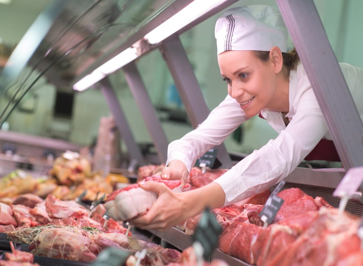 Butcher,Reaching,Meat,Out,Of,Counter