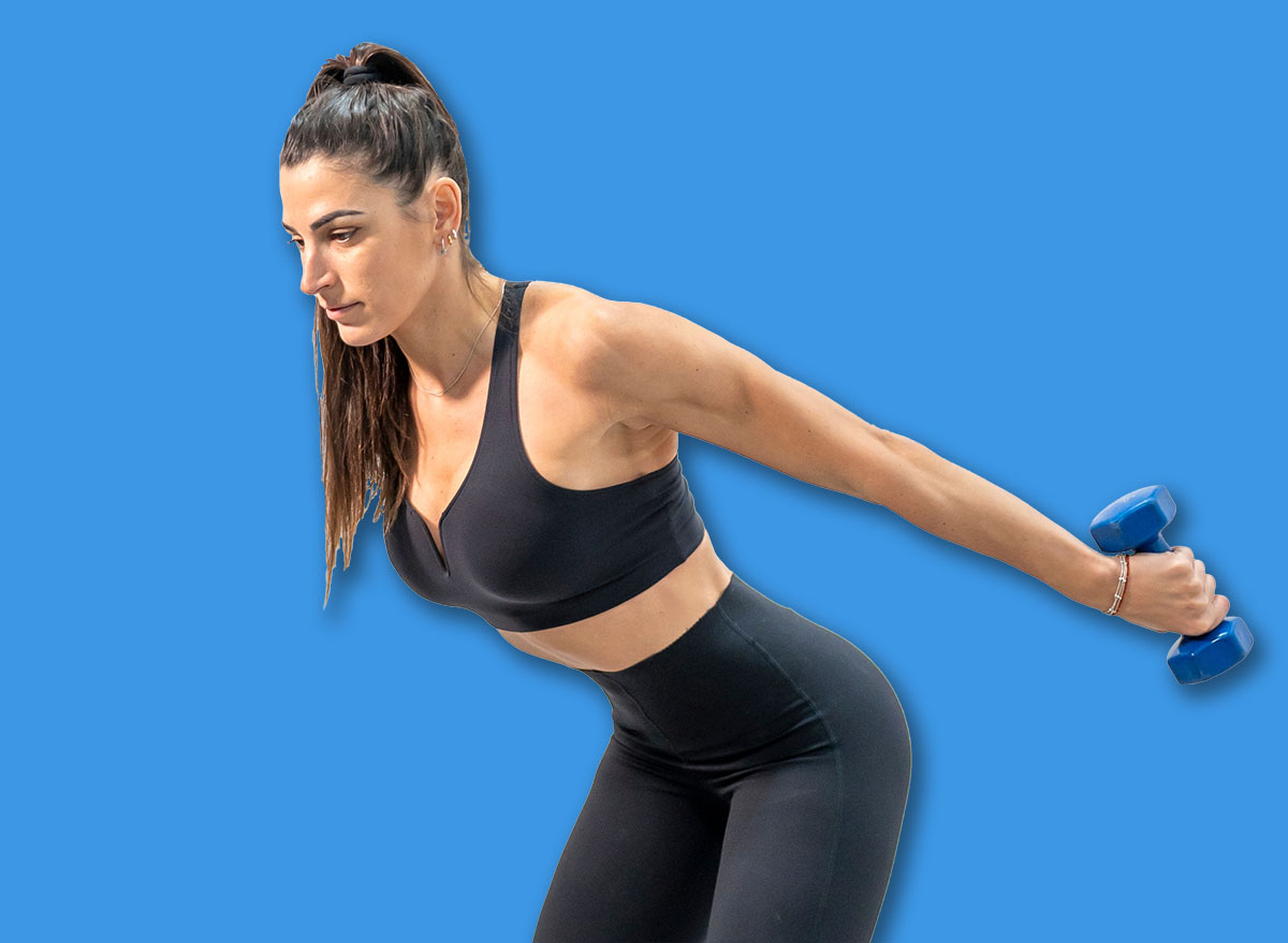 Woman doing tricep kickbacks using dumbbells with arms extended backward and leaning forward