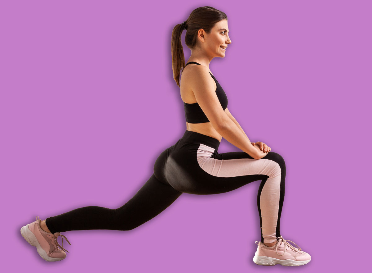 Side view of slim woman doing stretching legs workouts for better flexibility, lower body exercise, wearing black sports top and tights. Full length studio shot illuminated by sunlight from window.