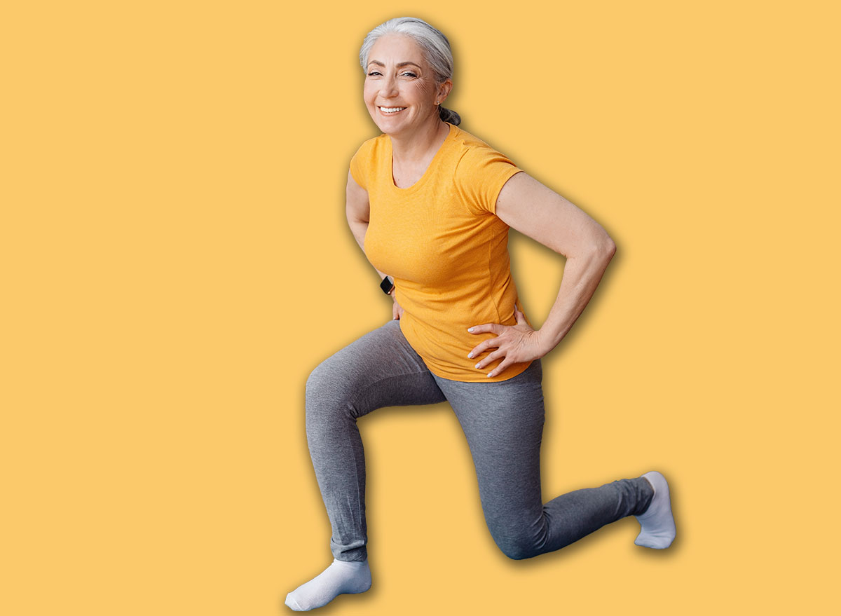 Full length portrait of sporty senior woman keeping fit, exercising on yoga mat in living room and smiling at camera. Staying healthy on retirement