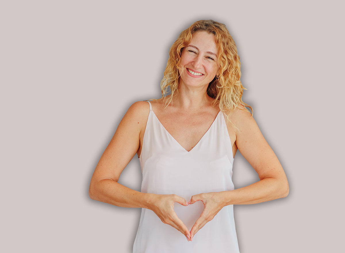 Beautiful woman shows heart in abdomen / copy space.