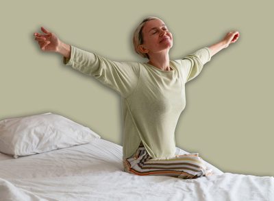 Happy Refreshed Woman 40s waking up from Bed in the Morning by Stretching hands - concept of positive emotion, rejuvenation and relaxation