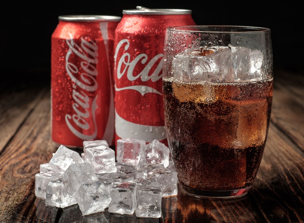 can of coke soda next to glass