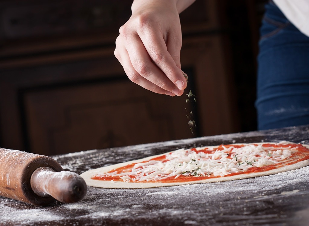 Sprinkling cheese on pizza dough - foods high in carbs