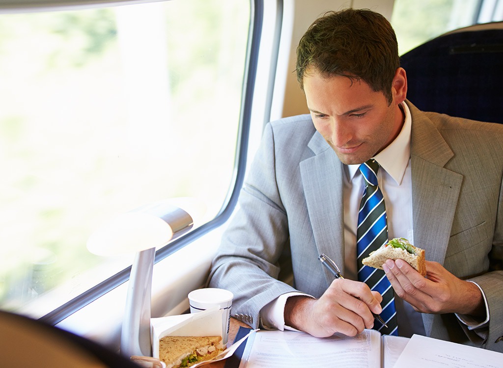 Man on train eating lunch and working