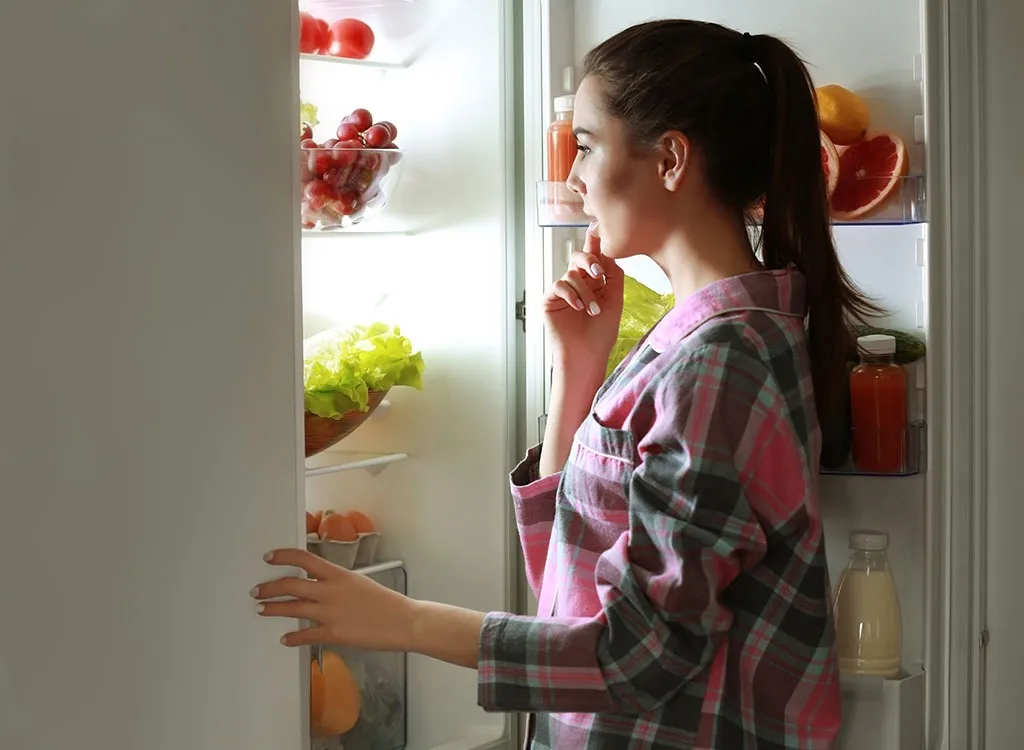 Woman looking in refrigerator late at night