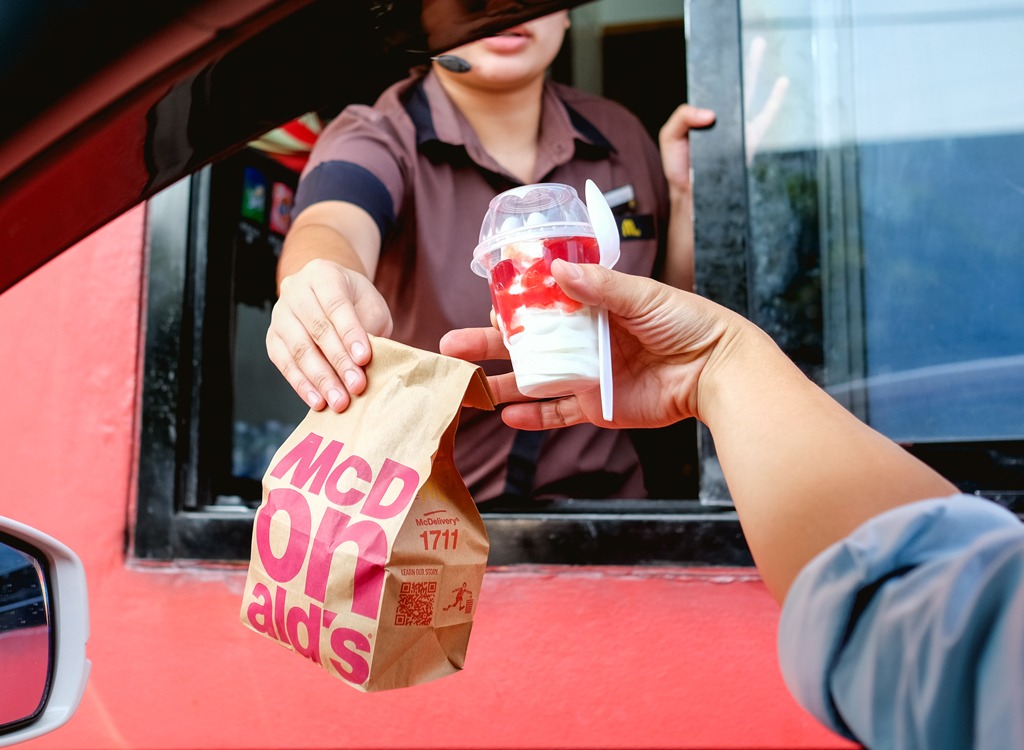 Fast food worker handing customer McDonald's ice cream sundae from drive thru
