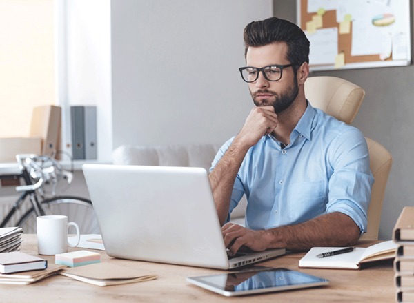 Man in glasses working on laptop