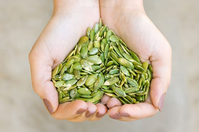 Woman holding pumpkin seeds in hands