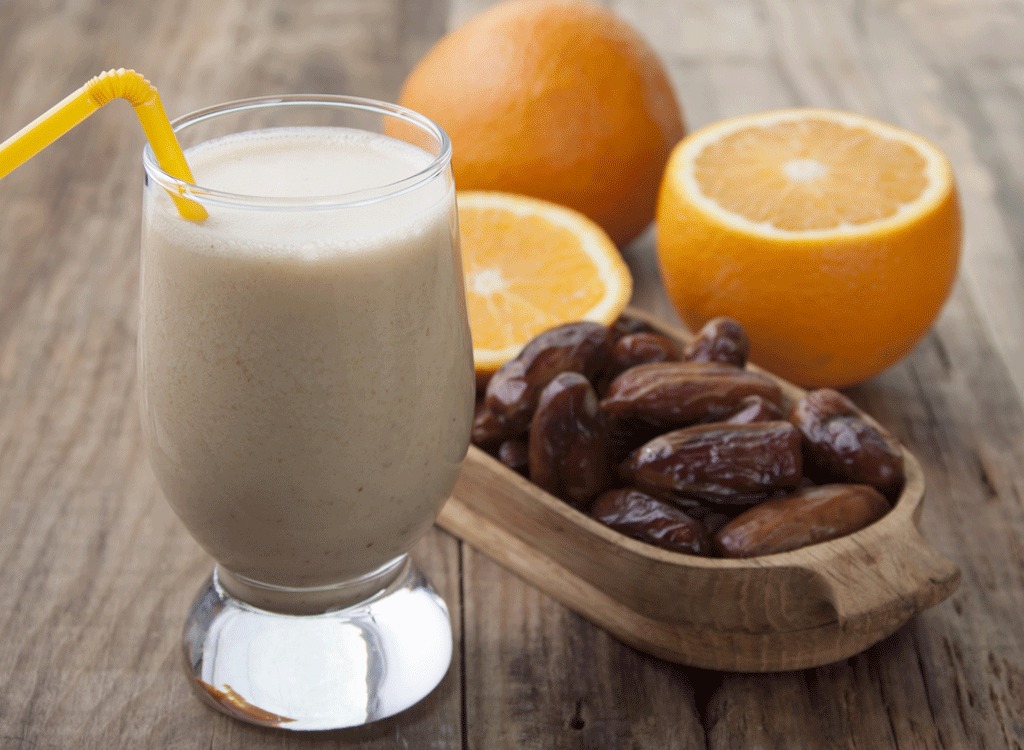 Date and orange smoothie with an orange straw, a smoothie made with foods to prevent colds