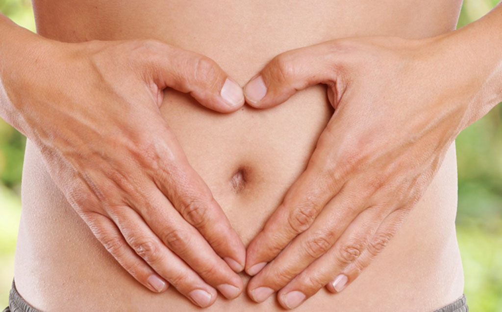 Woman making heart shape with hands on stomach