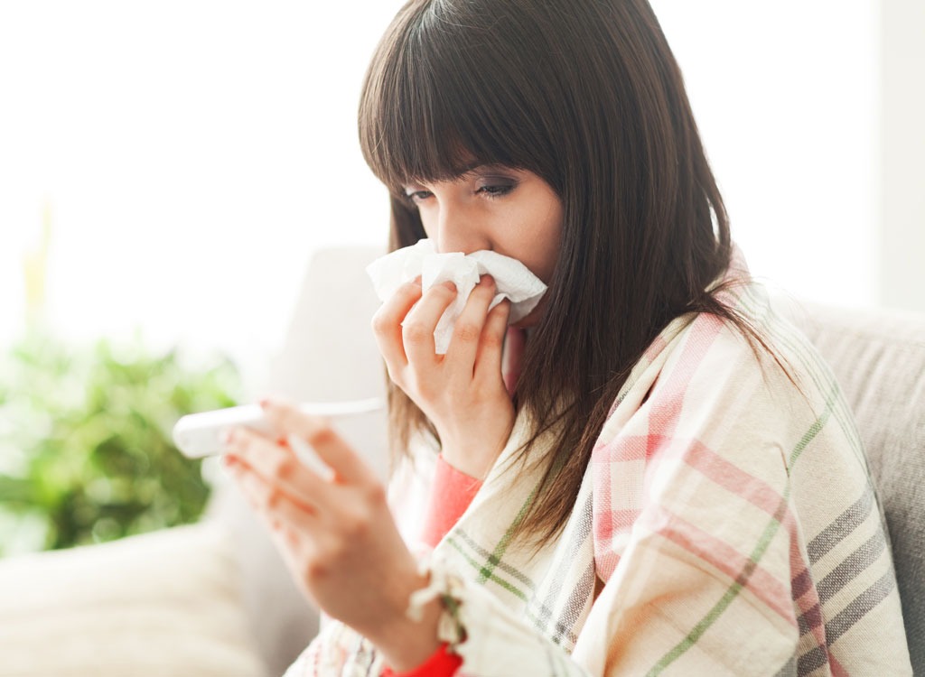 sick woman on couch thermometer