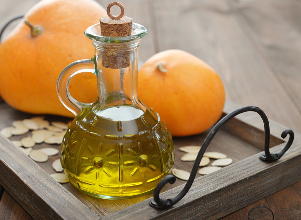 pumpkin seed oil in bottle with pumpkin seeds and pumpkins