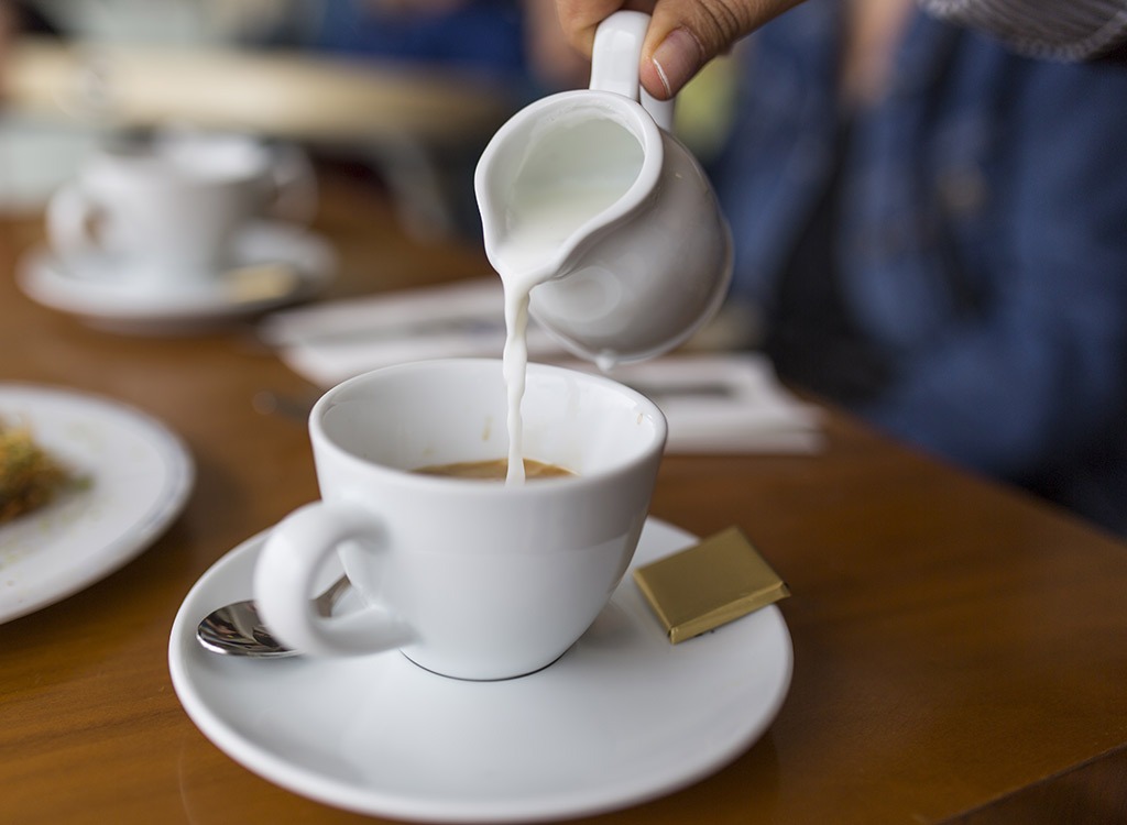 pouring creamer into coffee