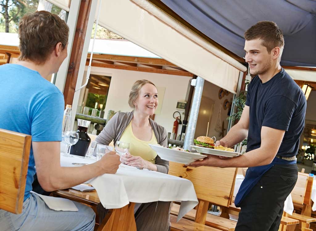 waiter bringing a smiling couple their meal