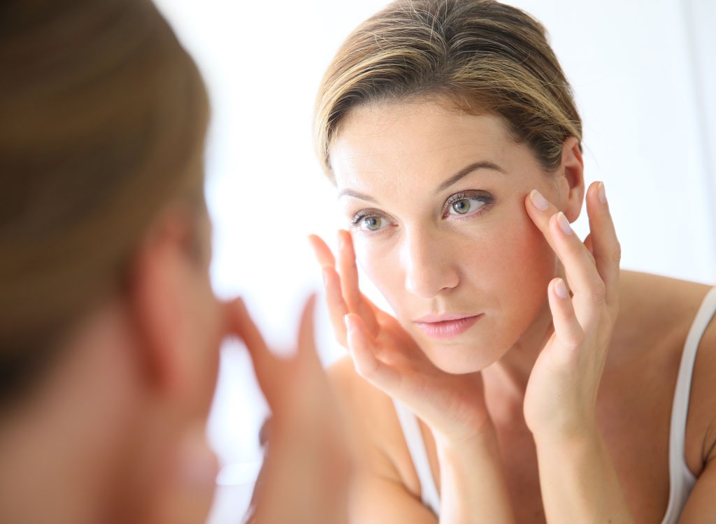 Woman looking in mirror - benefits of lemon