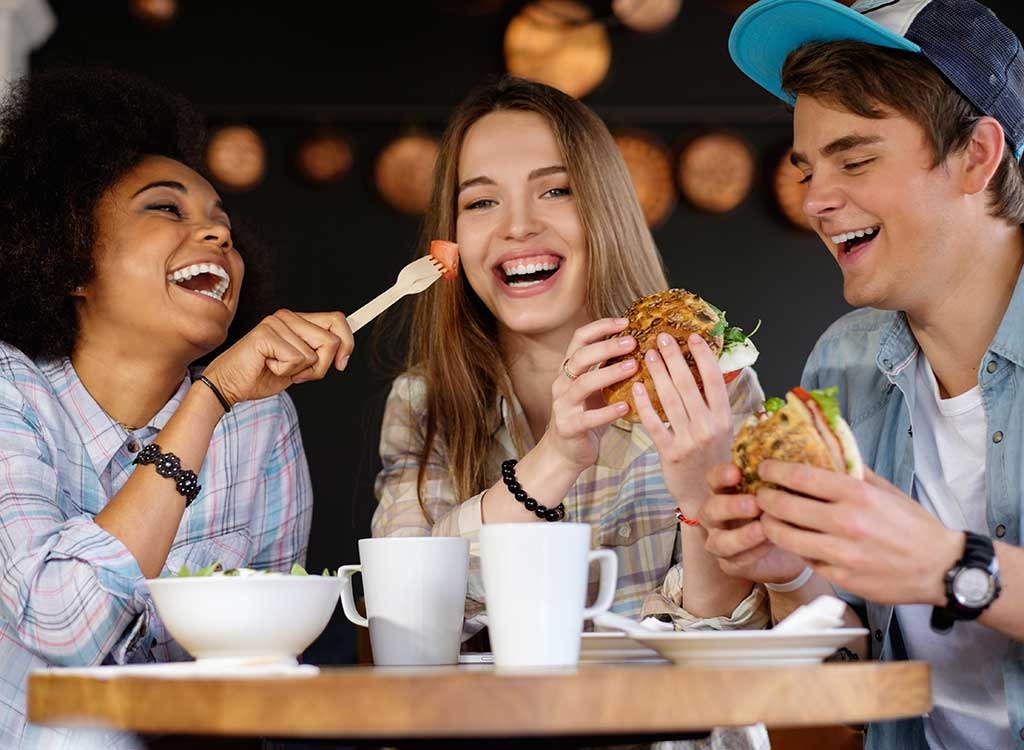 Amici ridere insieme mentre si mangia